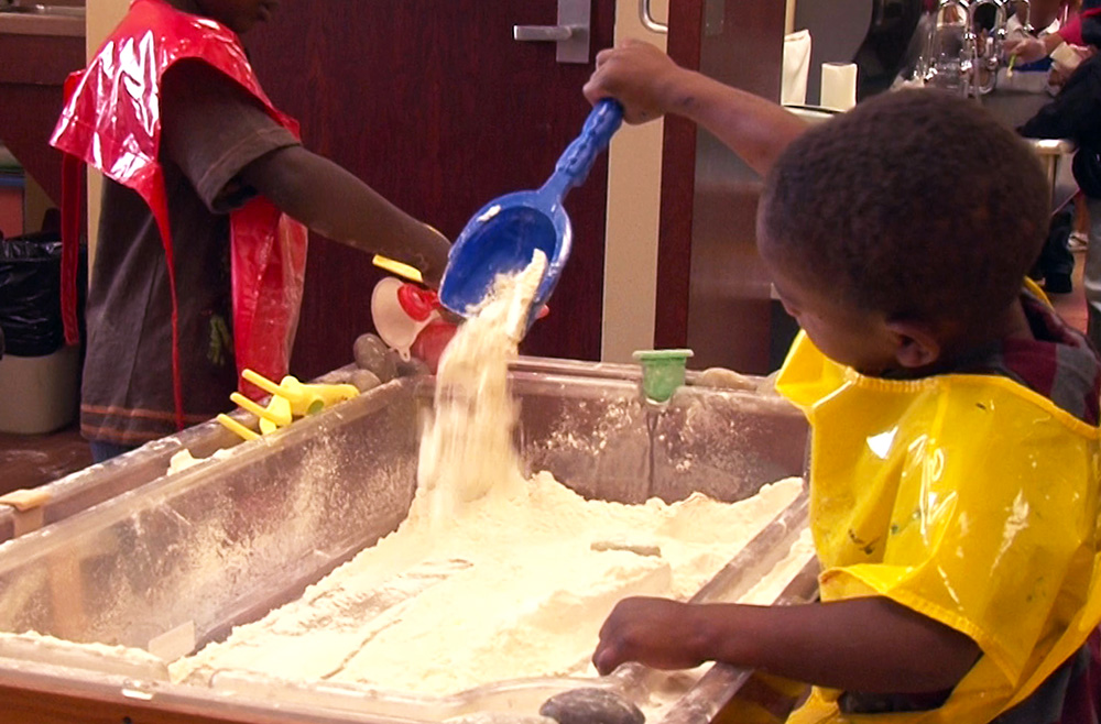 Two boys learn while playing in a sensory table